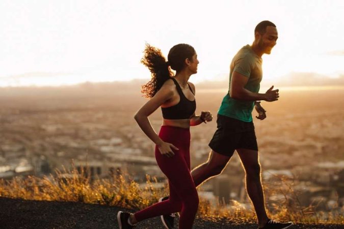 Personnes en train de courir le matin sur une colline avec vue sur la ville au lever du soleil