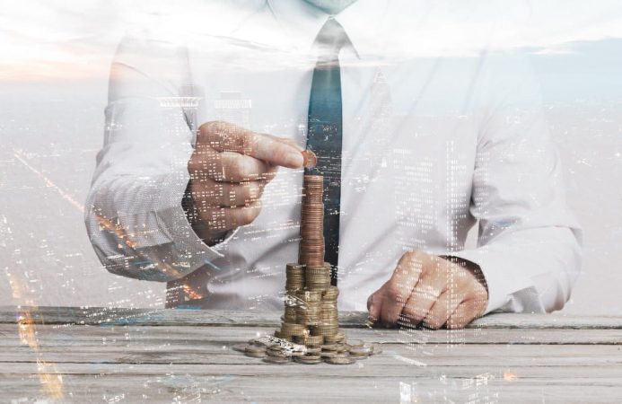 Homme d'affaires empilant des pièces de monnaie, avec une double exposition d'un paysage urbain, illustrant le concept de mécanique du levier financier.