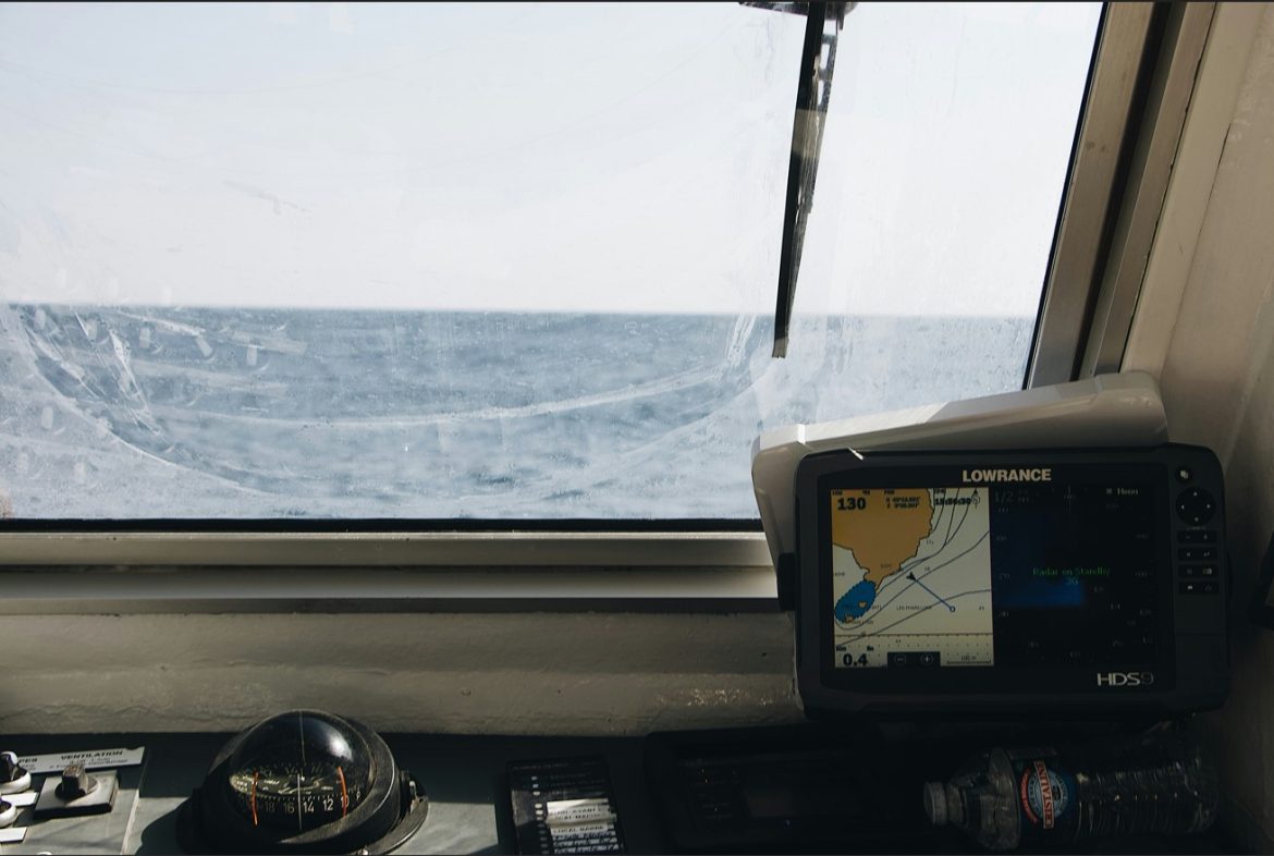 Vue depuis le cockpit d'un navire montrant un écran de navigation Lowrance et un compas, illustrant l'évolution de la technologie maritime IA en mer.