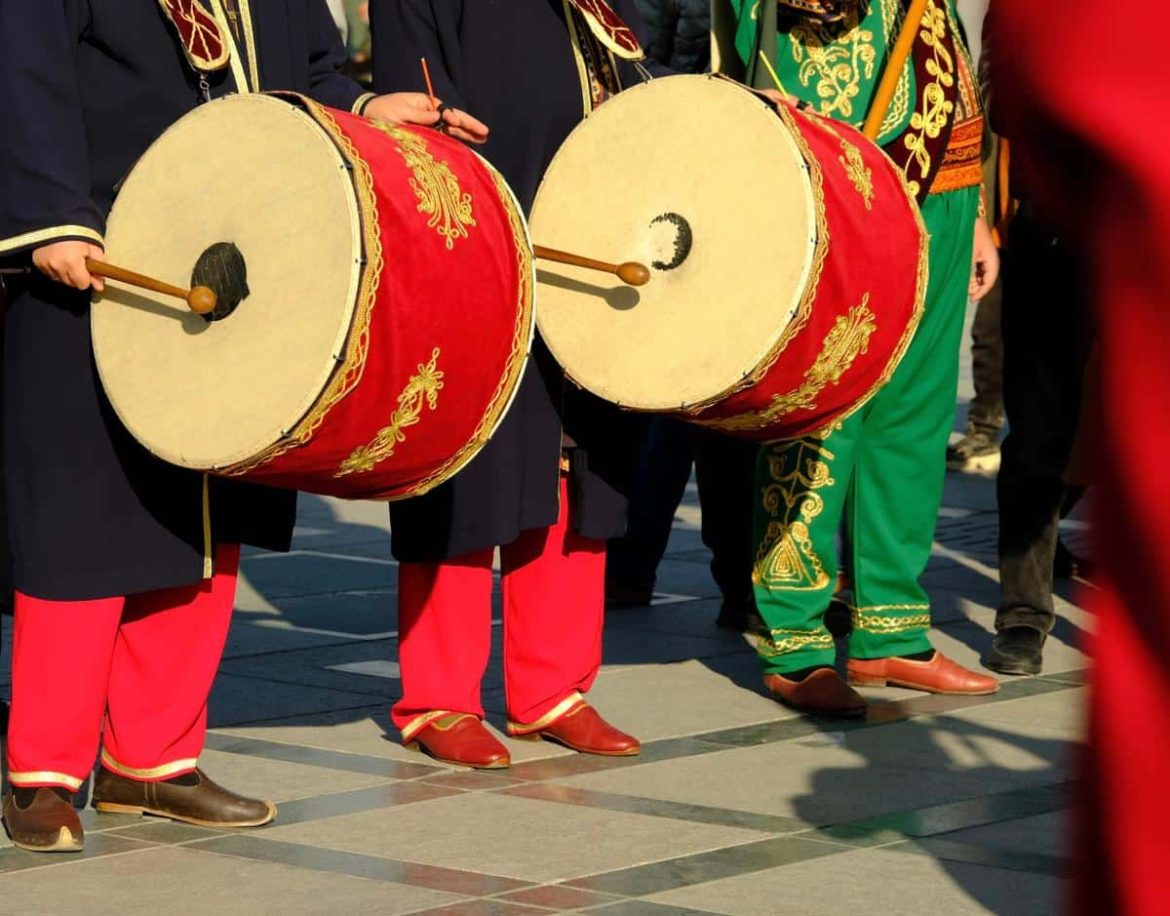 Musiciens en costume traditionnel jouant des percussions lors d'un défilé culturel en plein air.