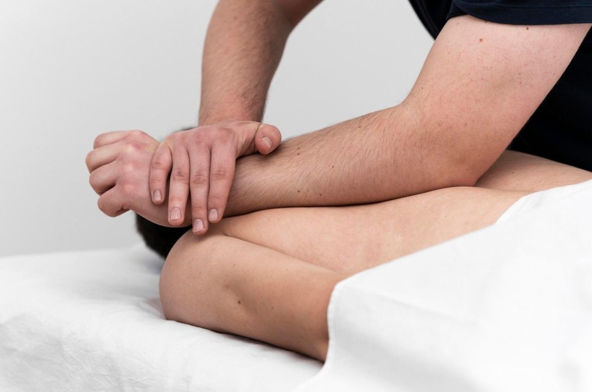 Praticien appliquant une pression forte avec l'avant-bras sur le dos d'un patient lors d'un massage tissus profonds adapté pour qui souffre de tensions musculaires.