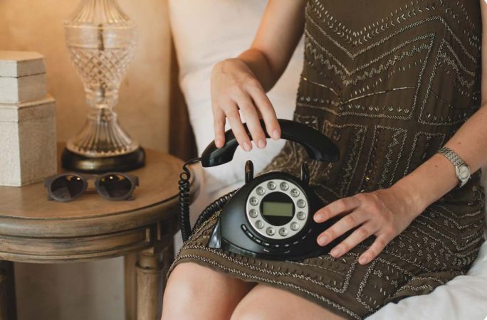 Une invitée décrochant un téléphone rétro noir, une alternative originale livre d'or mariage pour enregistrer des messages vocaux.