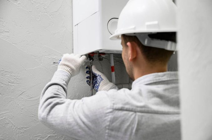 Un technicien en casque de chantier installe un système thermique dans le cadre d'un prêt à taux zéro installation chauffage.